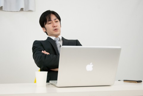 パソコンを眺めている男の写真