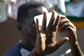 左手で紙を顔を前に右手で制止する男性