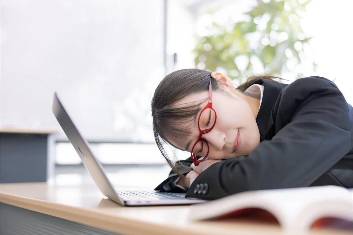机に突っ伏して仮眠を取る学生のイメージ