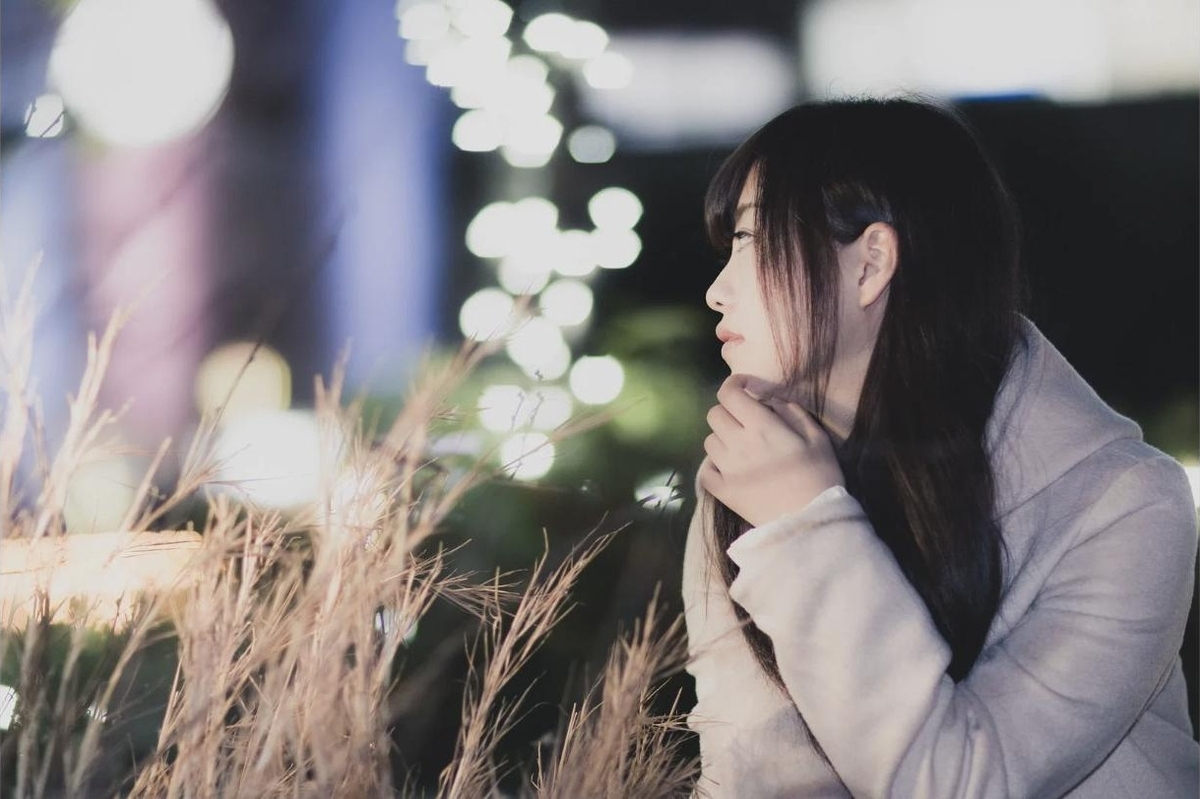 夜景の中、進路について考え込む女子大生