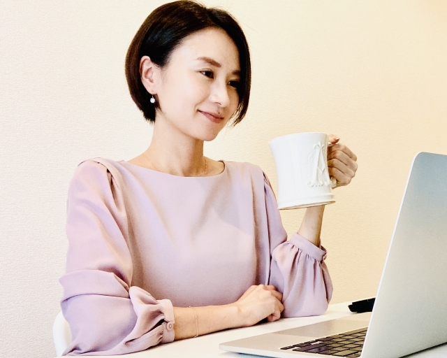 PCで動画編集作業中に飲み物を飲んで休憩している女性