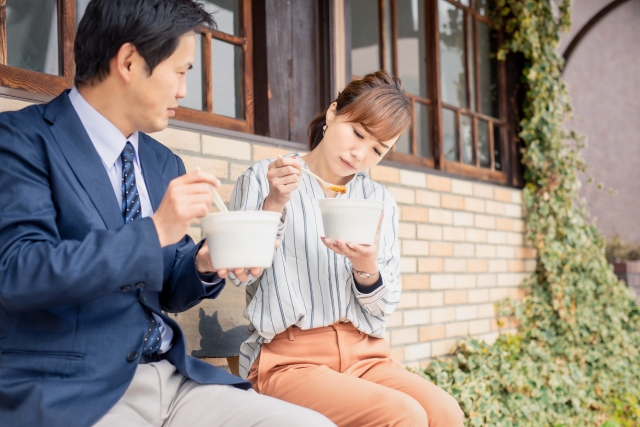 ダイエットに気遣いながら男性とベンチでお弁当を食べる女性