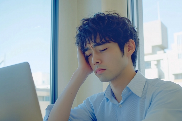 職場でパソコン画面を見ながら悩んでいる男性ITエンジニア