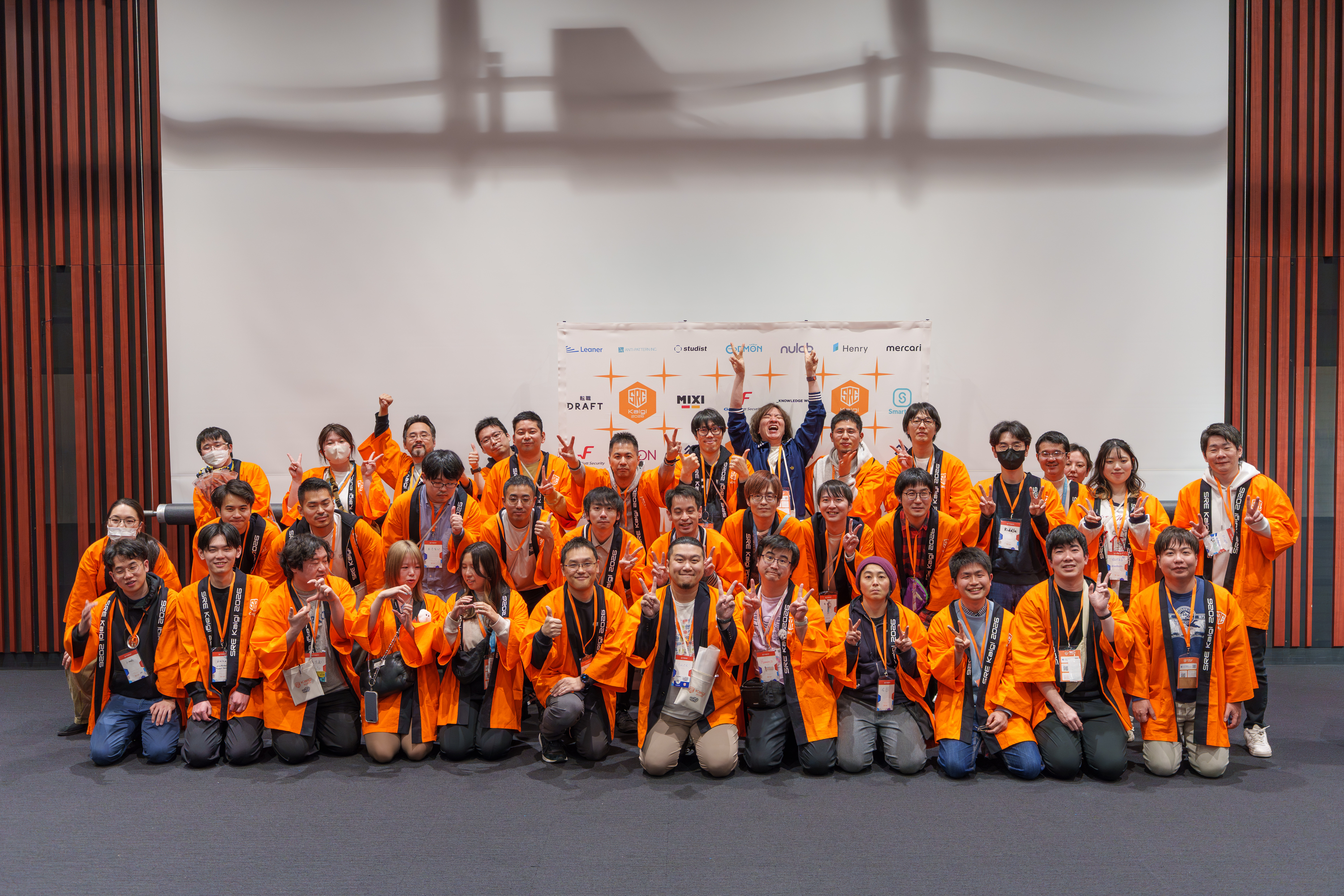 SRE Kaigi 2026のスタッフ全員によるオレンジの法被を着た集合写真