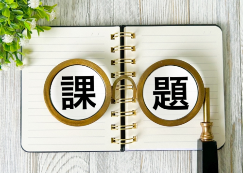 ファビピラビル個人輸入の課題を強調する画像。ノートの上に「課題」と書かれた文字が虫眼鏡で拡大されており、医薬品の個人輸入における安全性や信頼性の問題を視覚的に表現しています。