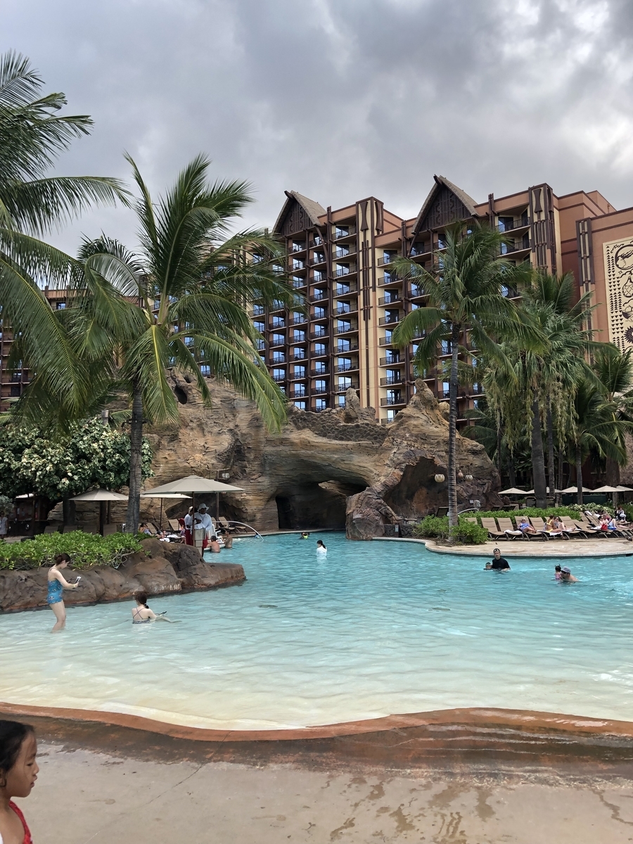 アウラニ・ディズニー・リゾートのプールからみたホテル。広いプールとヤシの木の向こうに、ディズニーらしいホテルが建っている。