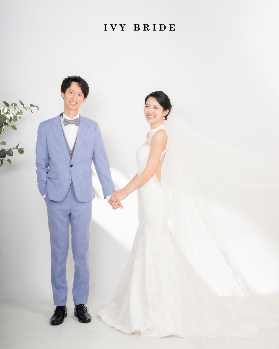 ウェディングフォト_おしゃれな白背景スタジオで手をつなぐスーツの新郎とマーメイドドレスの新婦