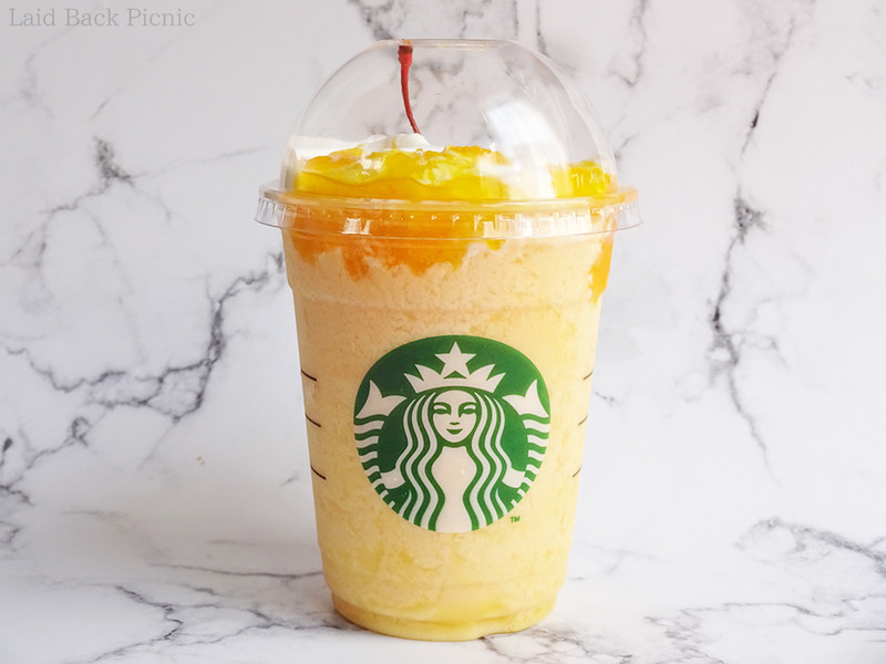 全体に黄色いフラペチーノには、ホイップクリームとフルーツ果肉ソース、チェリーのトッピング
