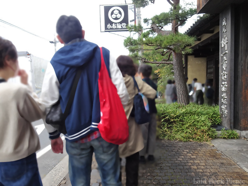 大きな木造の門の前の歩道に並ぶよう誘導される