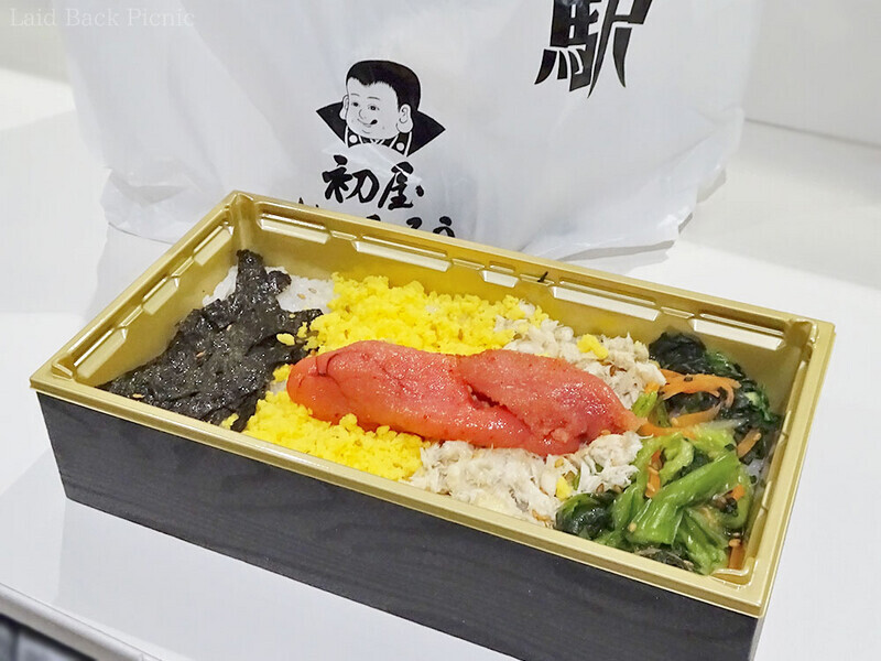 海苔 青高菜、炒り卵、鯖のほぐし煮、そこに丸ごと一本明太子が乗った弁当。