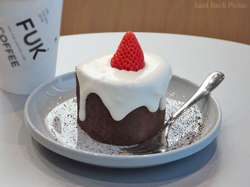 ダークブラウンのロールケーキの上に白いクリーム、その上に苺がひと粒。