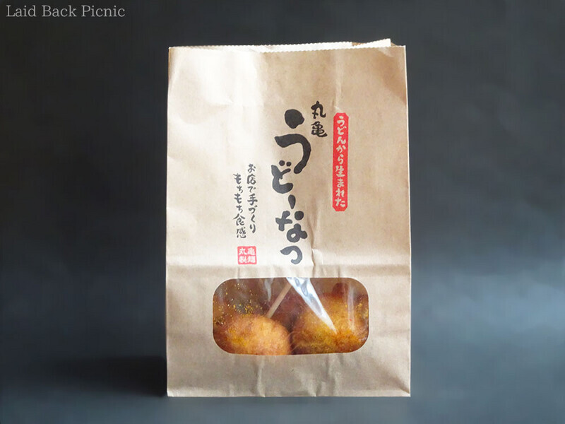 前に透明の窓がついた紙袋に『丸亀うどーなつ』のロゴ入り