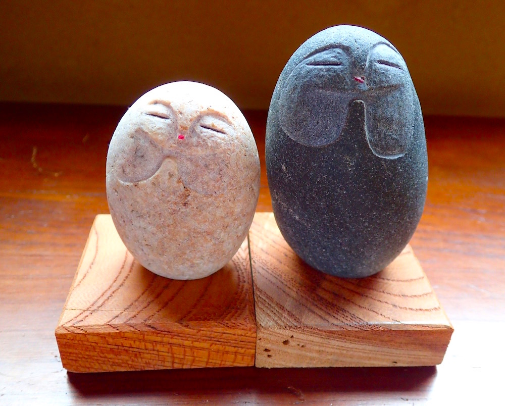 木の台座に座った石彫りのふたつの縁結び地蔵さま