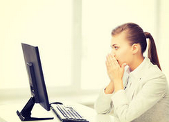 デスクトップPCの前で困惑している女性
