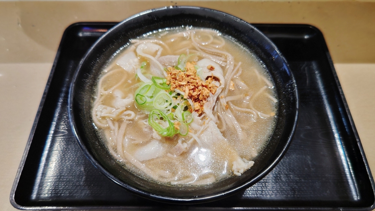 富士そばの肉骨茶（バクテー）そば。白濁スープにねぎと揚げニンニクなどの具材が乗る。