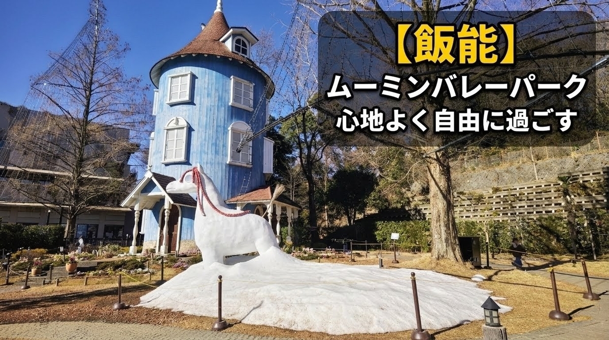 ムーミンバレーパークのムーミン屋敷外観。青い塔状の建物と前に立つ白いオブジェ、澄んだ青空と木々が広がる園内風景。