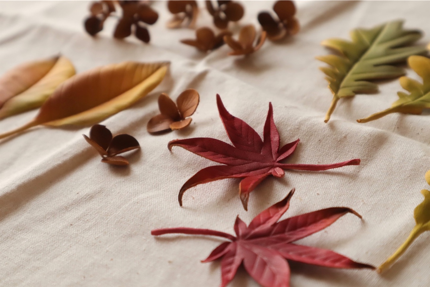 秋の散歩道をテーマに作られた、革の葉っぱ。紅葉したモミジや銀杏、枯れた紫陽花など、秋色の作品が並ぶ