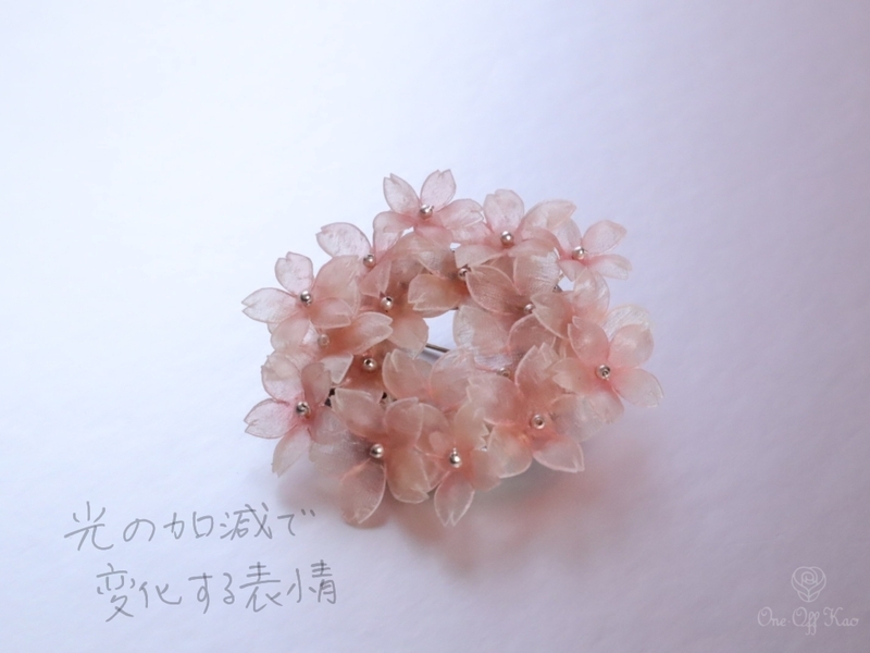 明るい場所で撮影された生革の桜ブローチ。桜の色合いが柔らかく見える。
