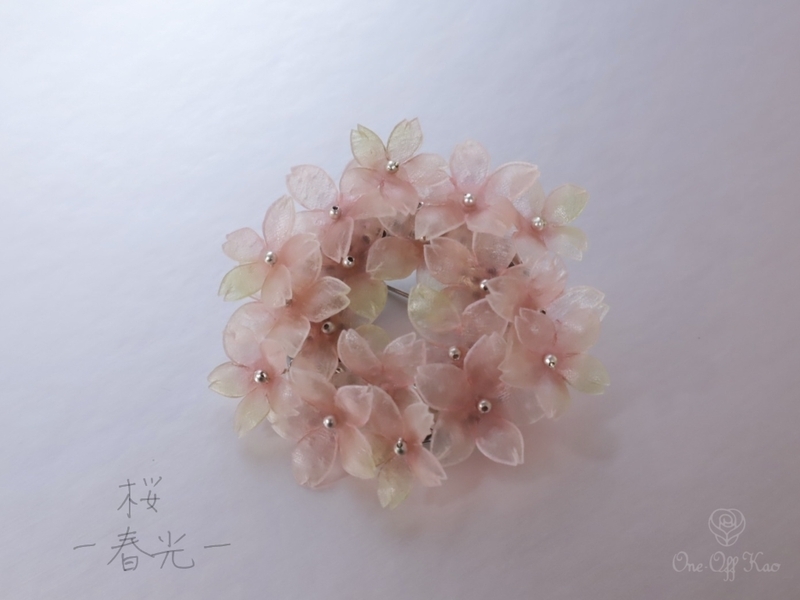 緑色のニュアンスが加えられた生革の桜ブローチ。