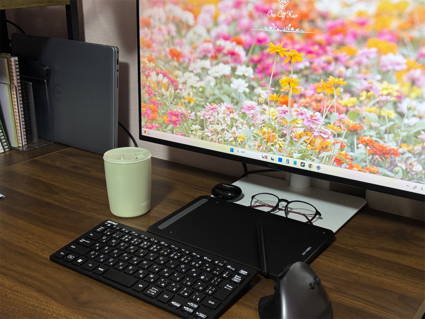 27インチモニターとサーモスタンブラー、ペンタブレット、ミニキーボードが並ぶPCデスク