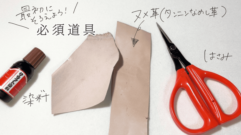 革花作りに必要な道具一式。クラフト染料、ヌメ革（タンニンなめし革）、はさみが並んでいる。手書き文字で「最初にそろえよう！必須道具」と書かれている。