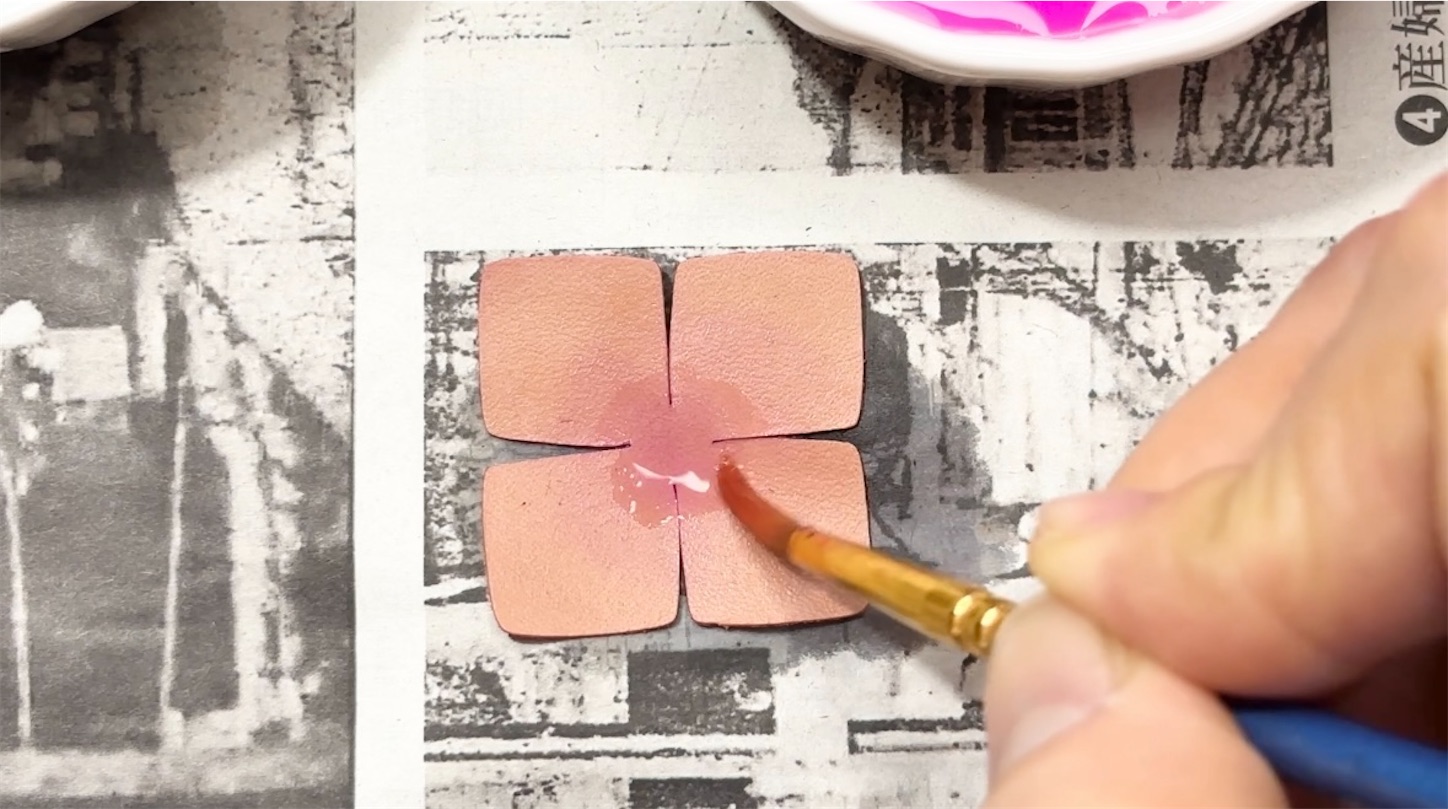 グラデーションをつけるために筆で中心部分に色を重ねている革花パーツの染色作業