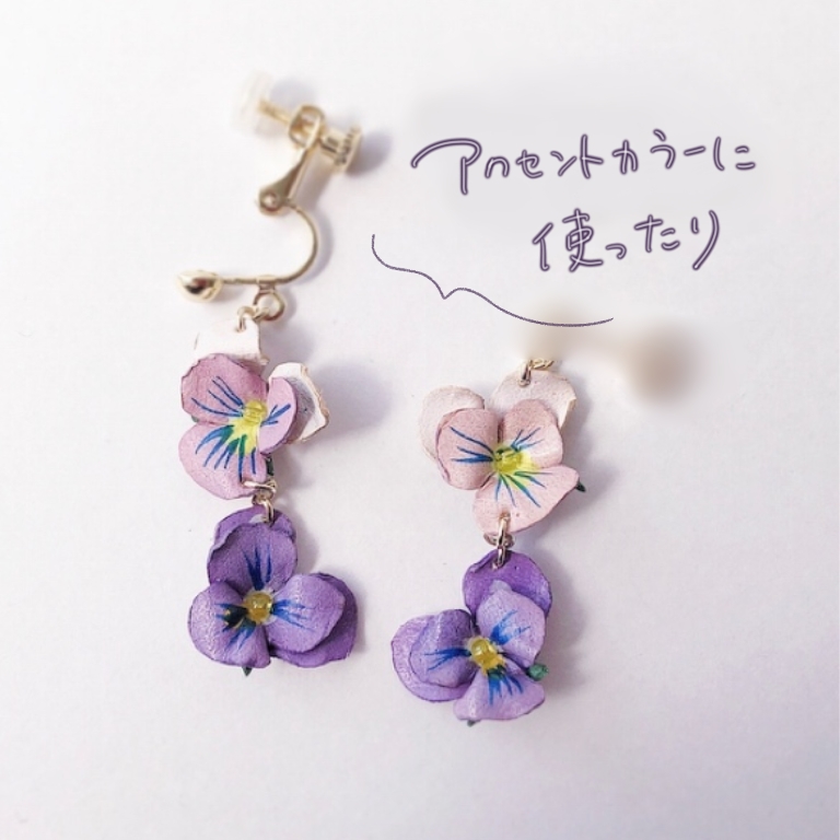 アクリル絵の具で着色したパンジー風の革花ピアス。淡いピンクと紫の花びらが2段になったデザインで、繊細な手描き模様が印象的。