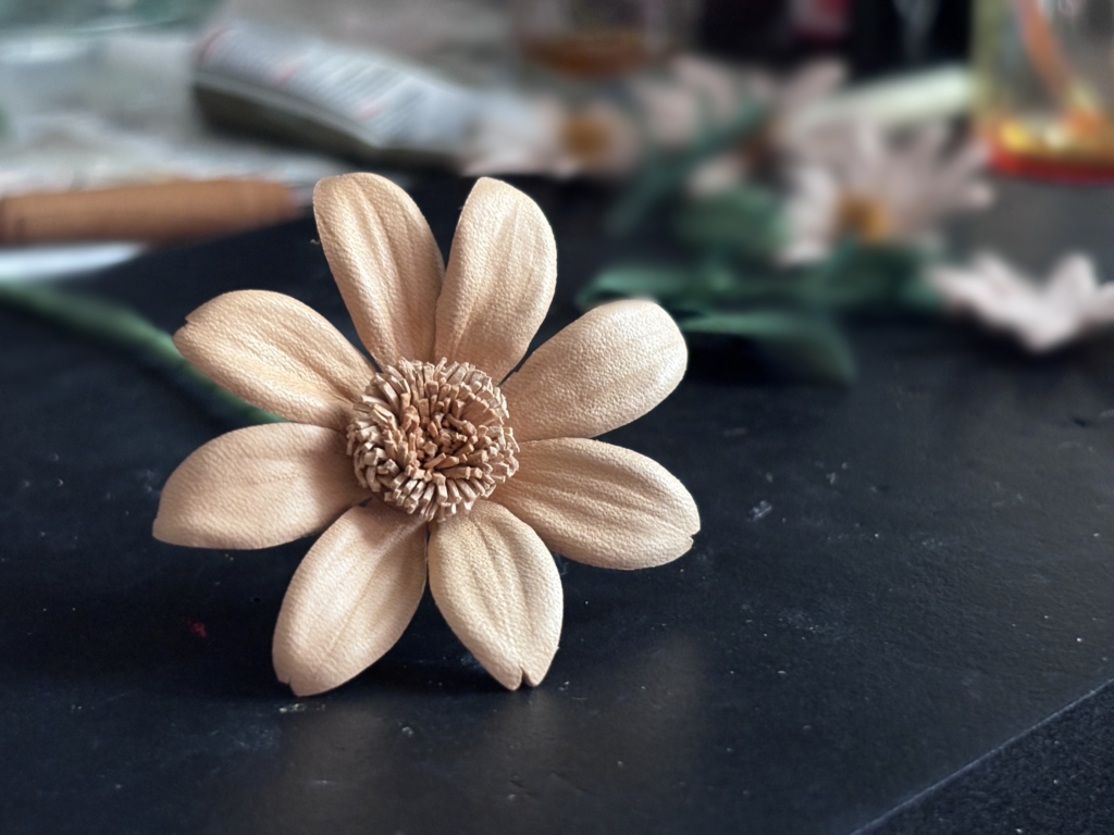 黒い台の上に置いた革花マーガレット。背景のぼかしで主役の花が引き立つ構図。