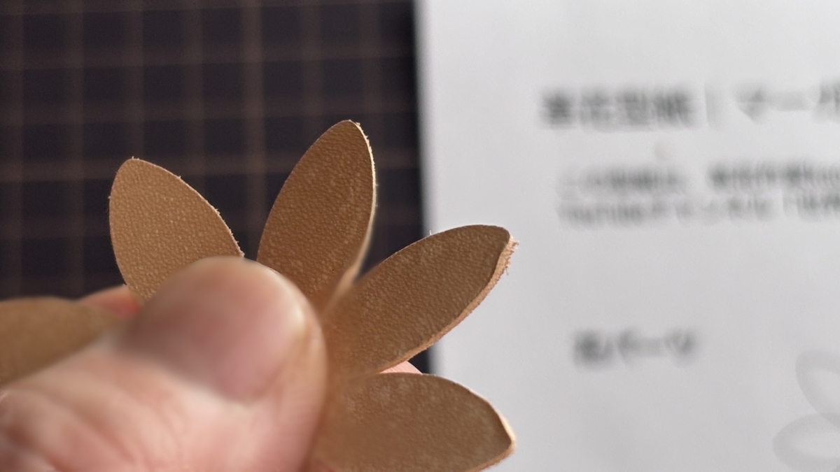 無料型紙でカットした革パーツを重ねて持っている場面。シンプルな花びらの形状が分かる。