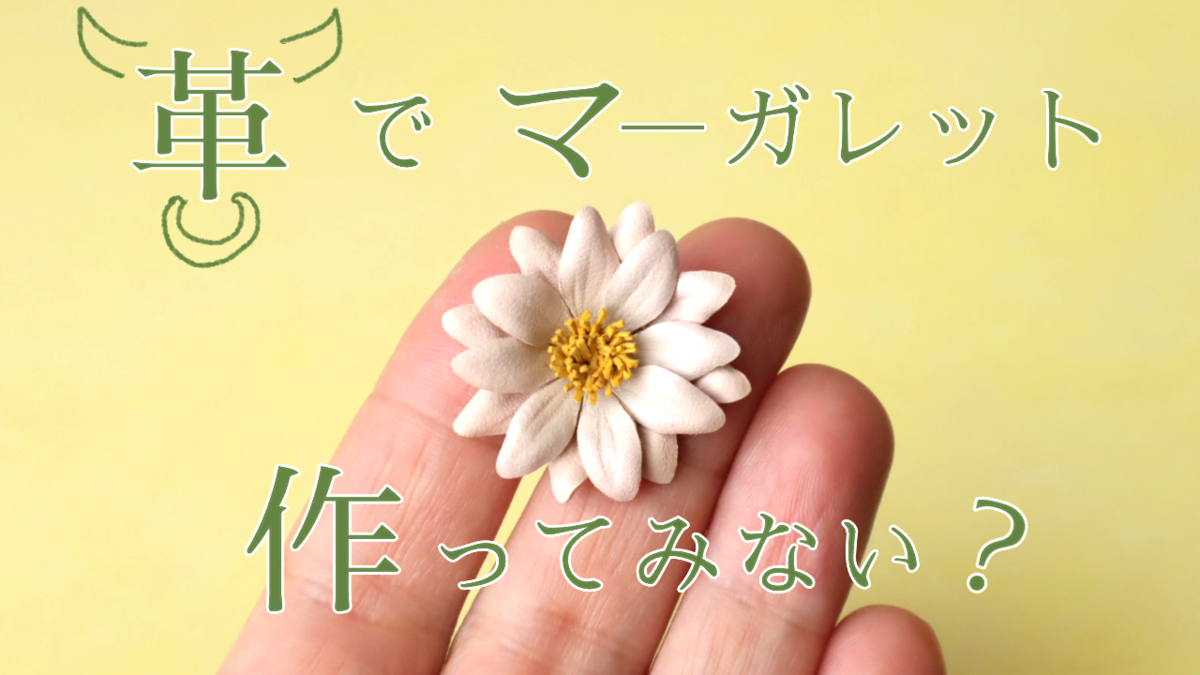 本革で作られたマーガレットの花一輪が手のひらに乗せられている。画像には、「革でマーガレット作ってみない？」と書かれている。