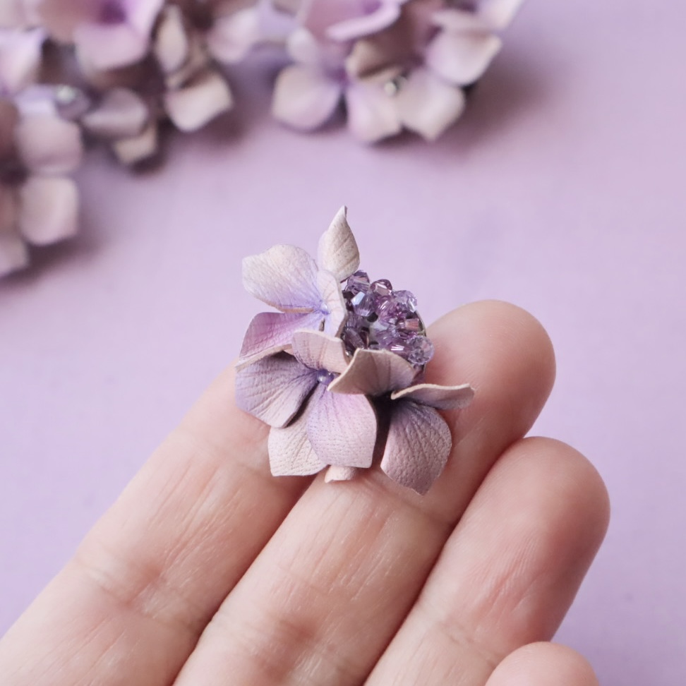 革でできた紫陽花のピアスを手にのせているところ