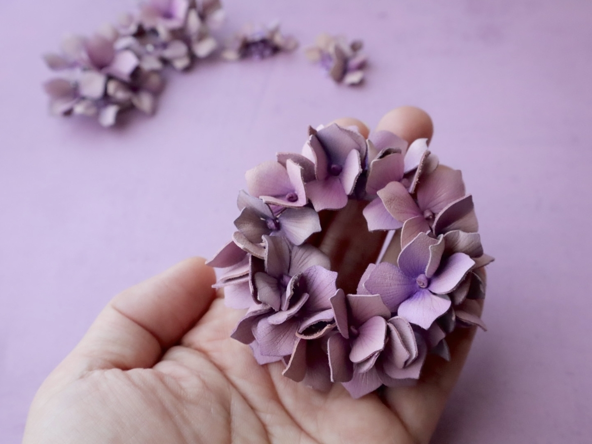 革で作られた革100％の紫陽花リースブローチを手に載せたところ。たくさんの紫陽花で作られていてとても華やか。