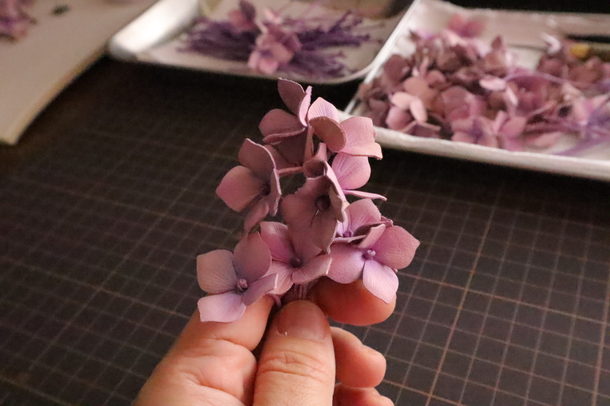 革で紫陽花を作っている作業中の画像。束になった紫陽花を手に持っている。