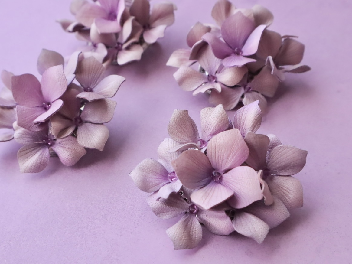淡い紫色の革花アクセサリー。たくさんの紫陽花が力強く咲き誇る様子が表現され、雨の日にも元気をくれるような佇まい。