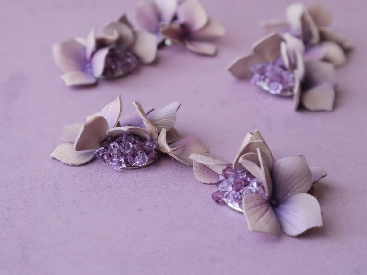 紫陽花の革花アクセサリー。小さな雨粒が花びらの上できらめき、宝石のような透明感と幻想的な美しさを放っている。