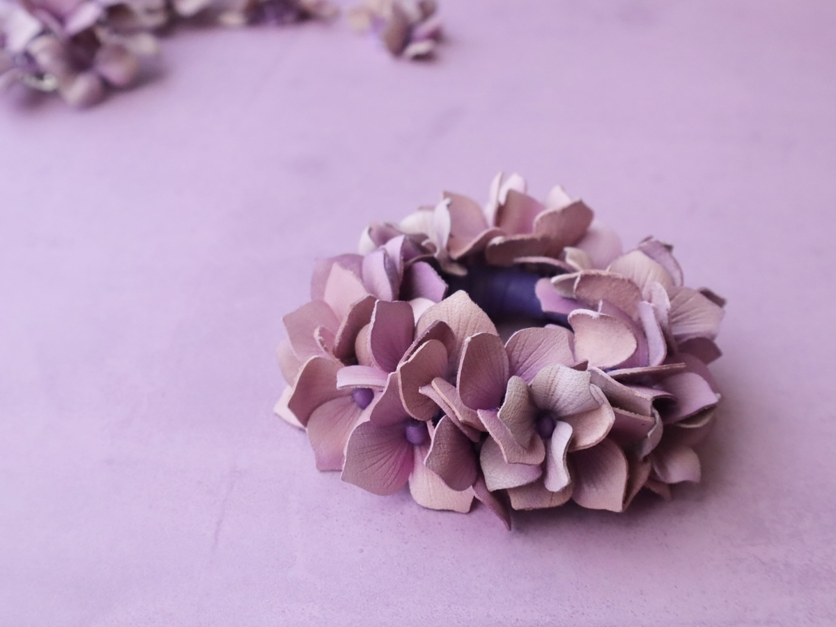 大輪の紫陽花をかたどった革花アクセサリー。繊細な花びらが幾重にも重なり、優雅で華やかな雰囲気を漂わせている。