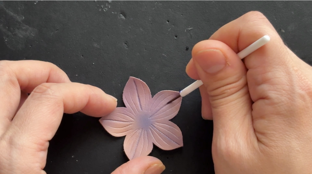 桔梗の形にカットした革をエアブラシで染めたあと、目打ちで花弁のしわをつけ、筆でしわの部分を染めている