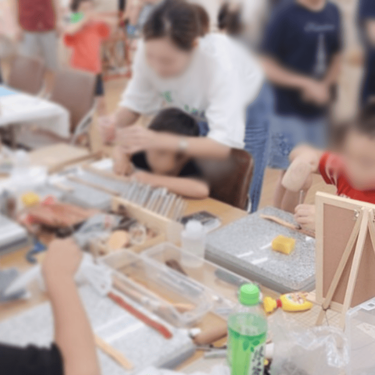 レザークラフトのワークショップの風景。子どもから大人まで真剣な表情で取り組んでいる。