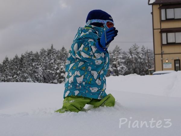 太ももまでの雪の中を歩く子供