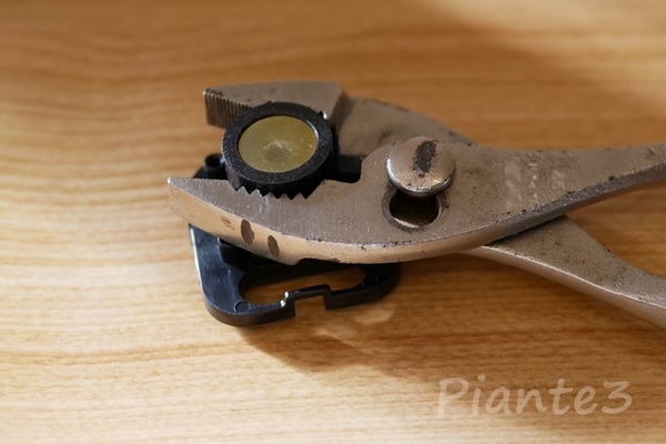 レンズをプライヤーで挟んでいる写真