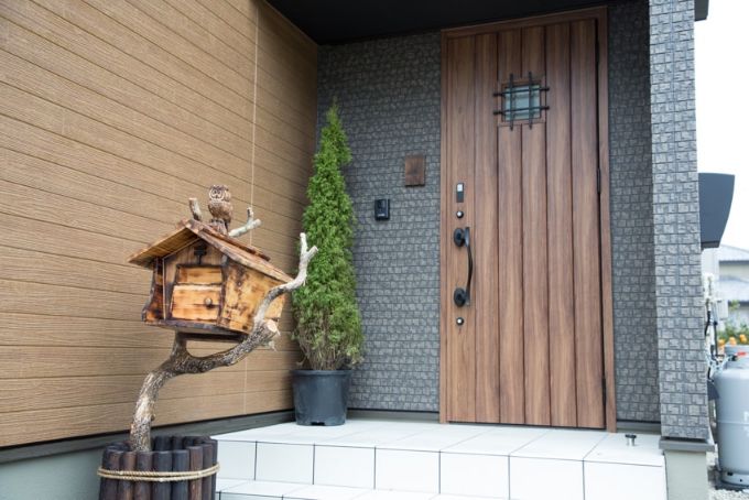 手作りの木彫りのポストがかわいらしい玄関外／注文住宅実例