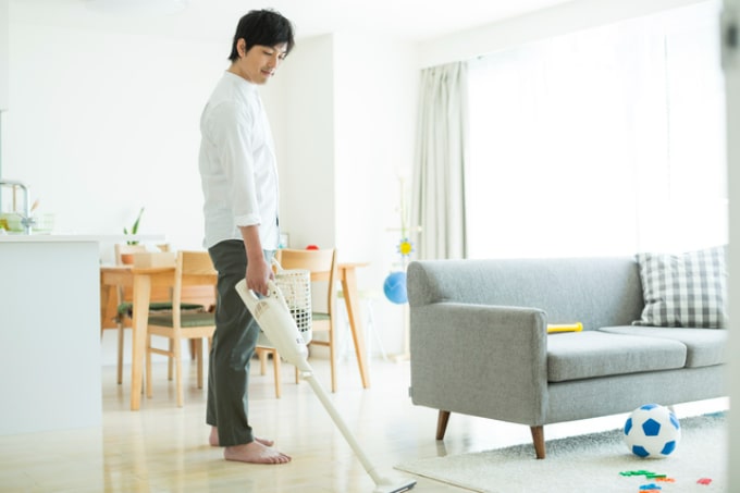 ワイヤレス掃除機をかける男性