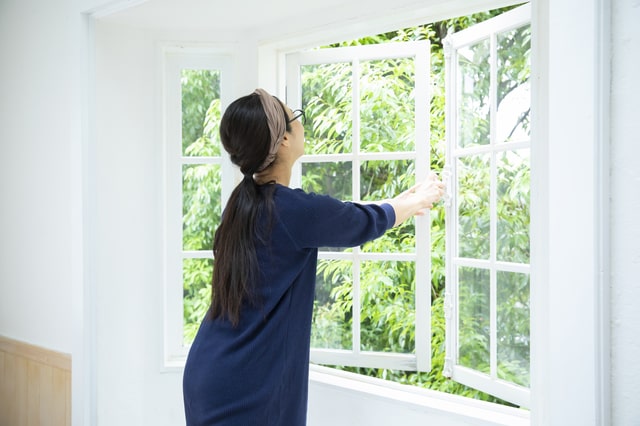 窓を開け寝室の換気をする女性