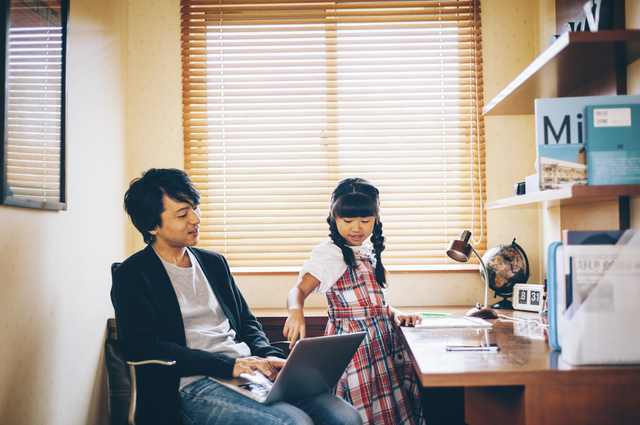 ひとつのデスクで作業する親子の写真