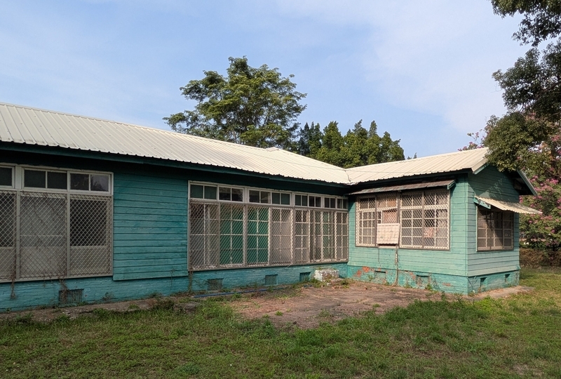 周辺に残る改修前の日式宿舎の外観で、外壁が戦後に塗り替えられ緑色になっている様子。