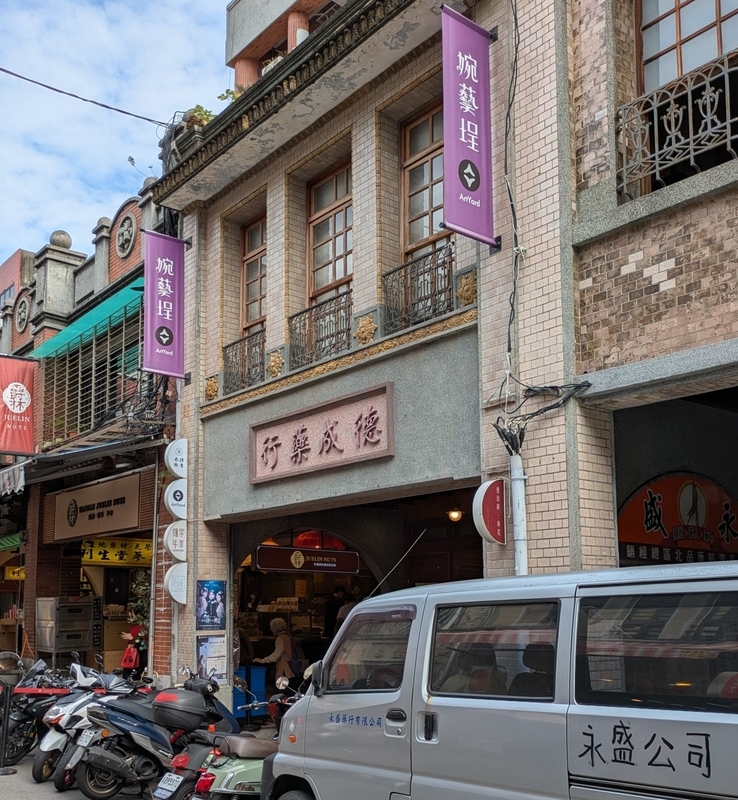 婉藝埕の外観とタペストリー。シューズやバッグを扱う店舗。