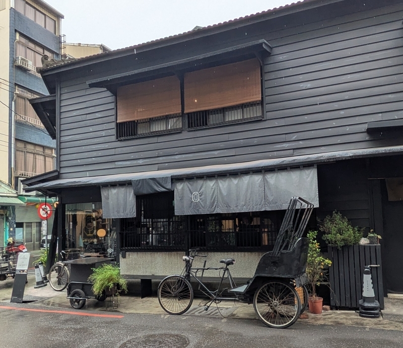 店の軒先に当時の三輪車や自転車が飾られ、嘉義の街並みに溶け込む新華美西装社の外観。