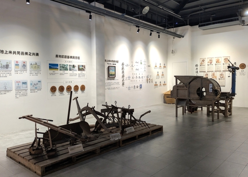 脱穀機などの農具展示と池上米の歴史紹介パネル。