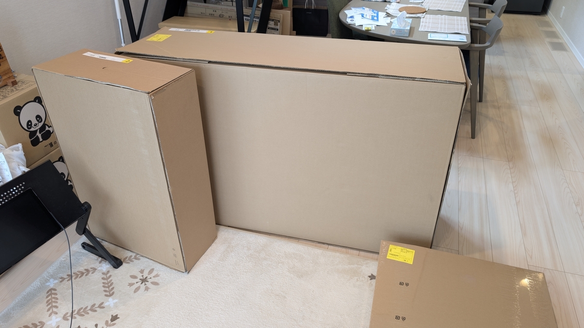 部屋の中央に未完成の家具が段ボールで梱包されておかれている