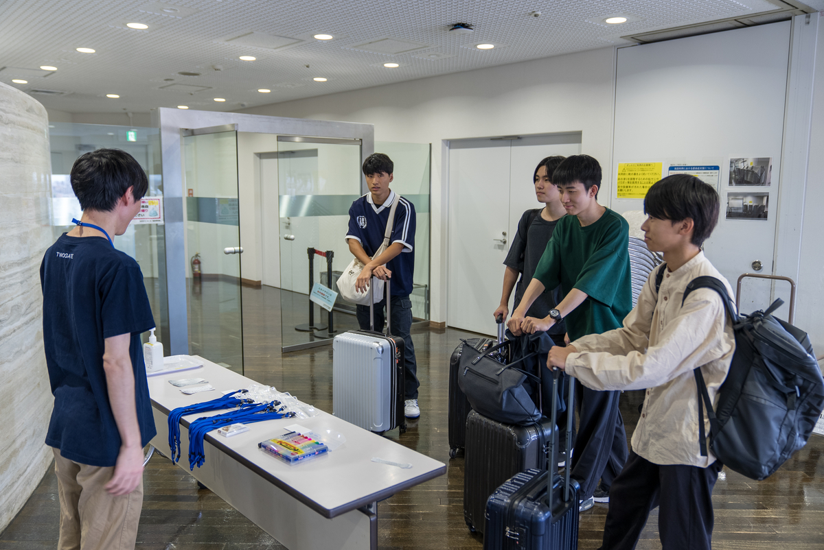 スーツケースを持って会場に集まってくる学生の写真